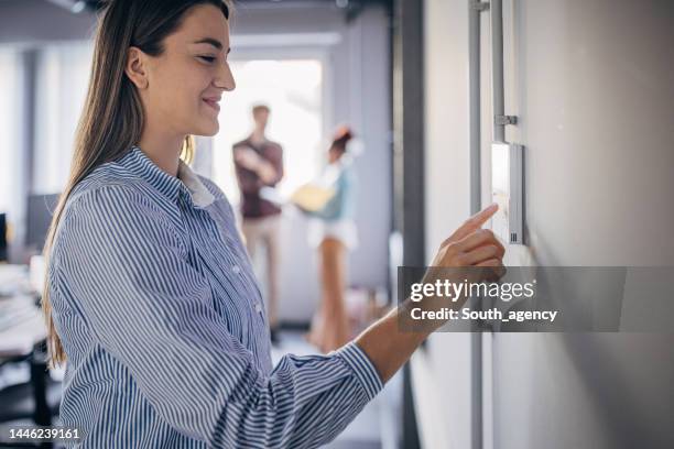 young woman changing temperature on thermometer in the office - energy efficient stock pictures, royalty-free photos & images