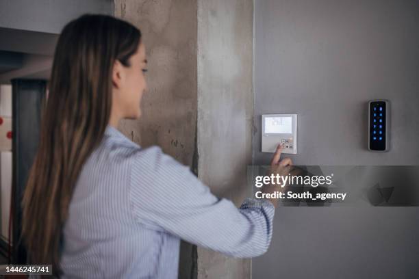 young woman changing temperature on thermometer in the office - thermostaat stockfoto's en -beelden