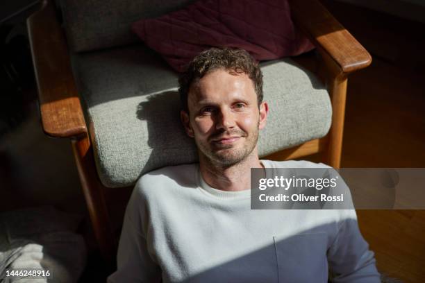 portrait of confident man relaxing at home - bodenständig stock-fotos und bilder