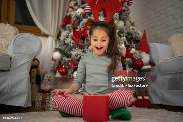 une fille de race blanche excitée ouvrant un cadeau de noël devant un arbre de noël - regarder vers le bas photos et images de collection