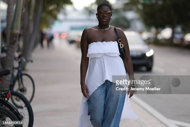 Kusikatz seen wearing a black dior saddle bag, a white offshoulder vokuhila top, oversized jeans and oversized shades on November 30, 2022 in Miami,...