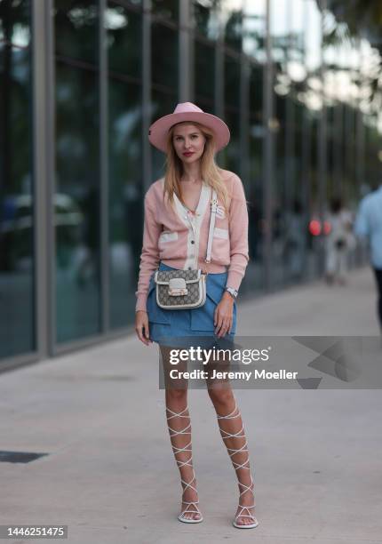 Anna Dianova seen wearing a Gucci bag, a Cartier santos watch, a blue mini skirt, a white and pink cardigan, a fedora and lace up sandals on November...