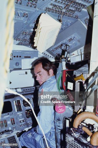 American astronaut John Young sitting at the commander's station on the port side of the forward flight deck of the Space Shuttle Columbia during...