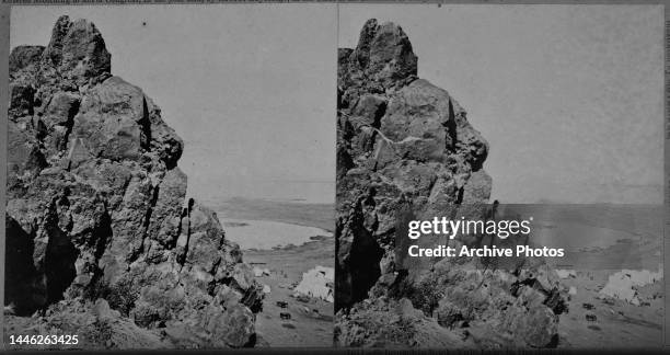 Stereoscopic image showing Schonschis Rock, with Tule Lake in the background, and tents and horses of a camp to the right of the frame, during the...