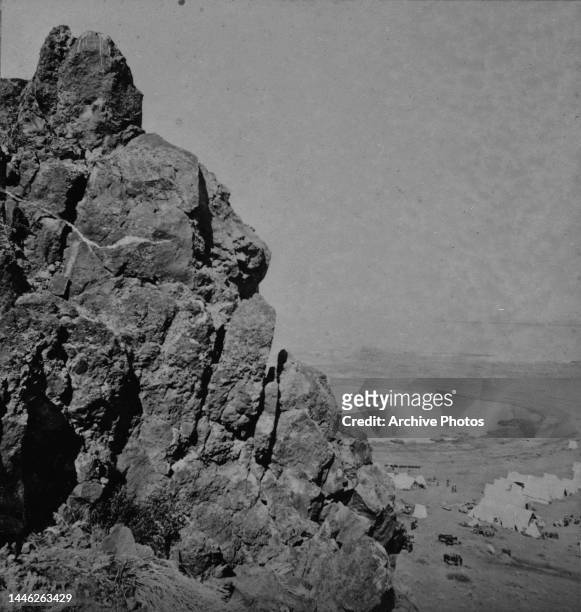 Schonschis Rock, with Tule Lake in the background, and tents and horses of a camp to the right of the frame, during the Modoc War in Siskiyou County,...