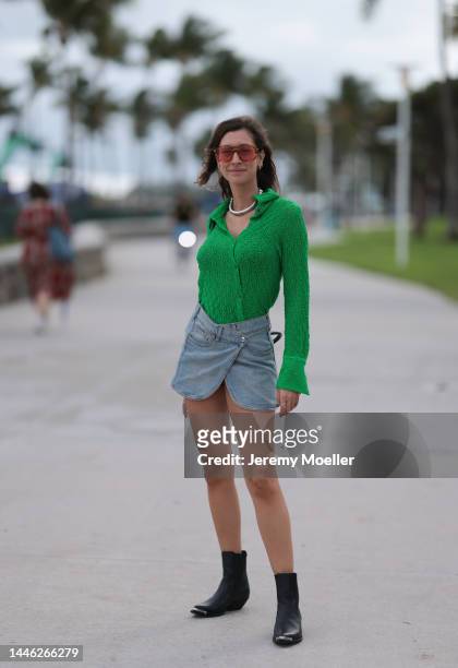 Guest seen wearing a denim mini skirt and a green blouse on December 01, 2022 in Miami, Florida.
