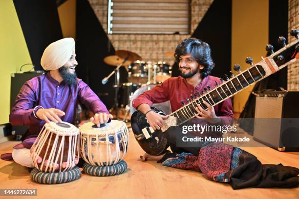 low-angle view of two young musicians playing musical instruments, tabla and sitar - tabla stock pictures, royalty-free photos & images