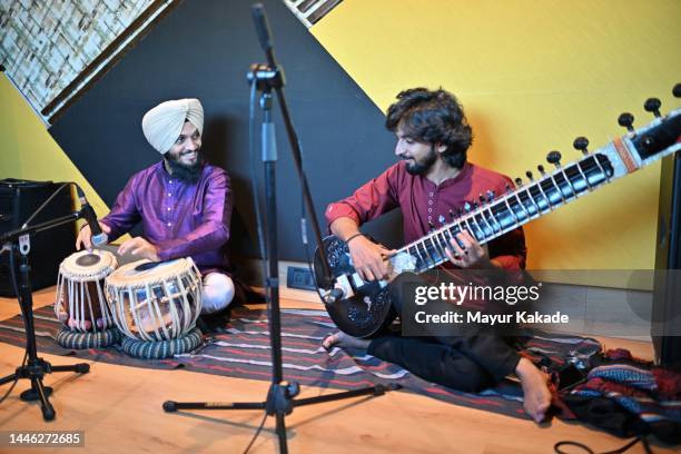 young sikh man playing the tabla along with another young man playing the sitar - sittar stock pictures, royalty-free photos & images