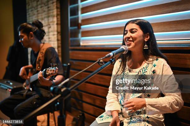 young woman singing indian classical song and the bass guitarist playing western music and creating a fusion - indian music 個照片及圖片檔