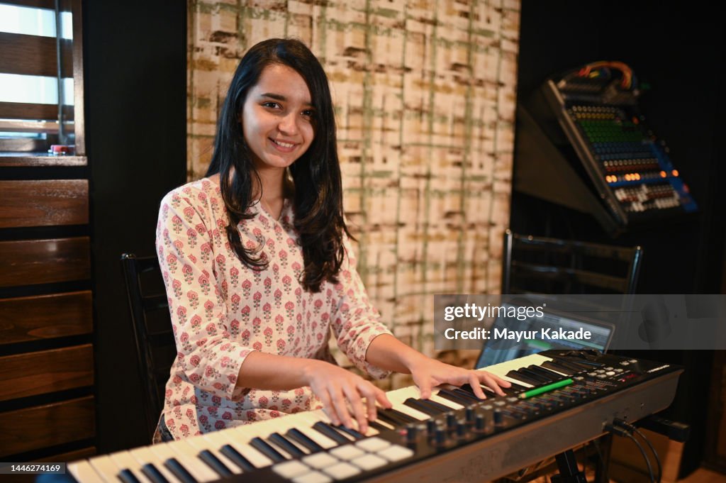 Young woman playing keyboard and looking at the camera and smiling