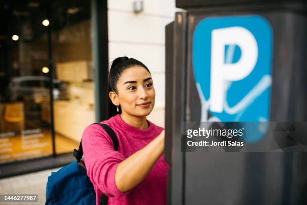 woman using a park meter - banco de españa fotografías e imágenes de stock