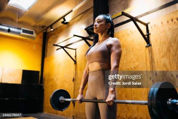 woman lifting bar bell in gym - weight lifting stockfoto's en -beelden