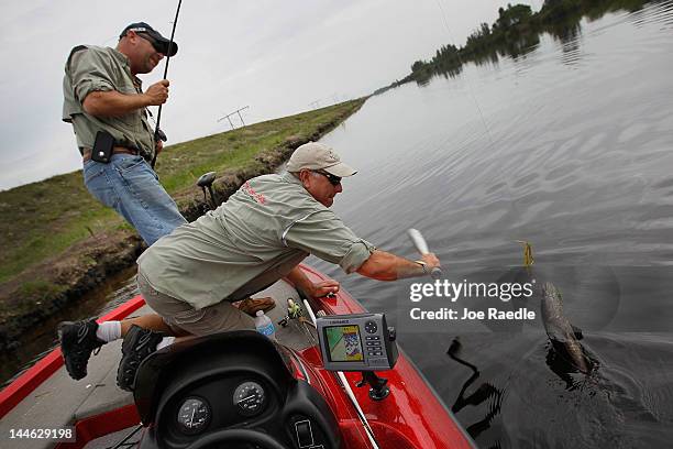 Dan Bieniek , from JD's Custom Baits, uses a bat to strike and kill a snakehead fish that Jason Calver caught while they were fishing in a canal on...