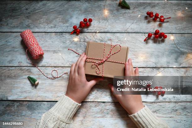 woman's hands packing christmas gift. top view. wooden background - gift bag stock pictures, royalty-free photos & images