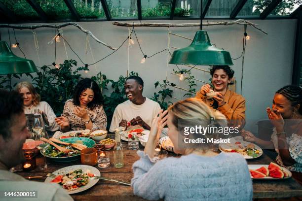 cheerful business colleagues having dinner together in garden - party inside stockfoto's en -beelden