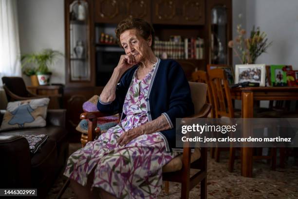 older woman sitting in her living room pensive and depressed - alzheimers stock-fotos und bilder