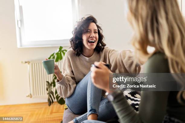 two young women having coffee and chatting having great time - vrouwenvriendschap stockfoto's en -beelden