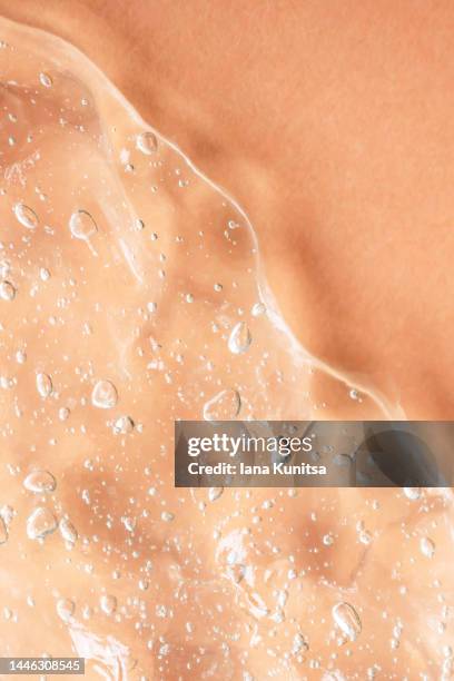 transparent smudged of liquid moisture serum for face on beige background. hydrating hyaluronic acid. antibacterial gel with bubbles. cosmetic products for makeup and skin care. cosmetology. - acide hyaluronique photos et images de collection