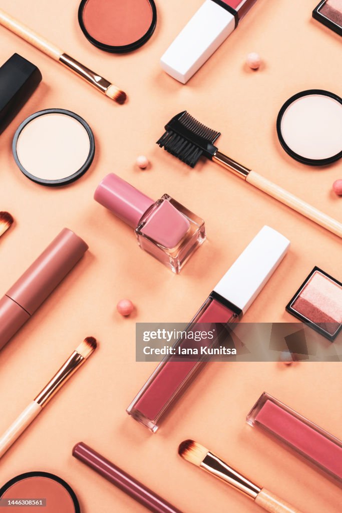 Set of different makeup accessories on beige, brown background. Knolling concept. Cosmetic products for skin care. Eyeshadow, blush, face powder, nail polish, brushes and lipstick. Vertical.