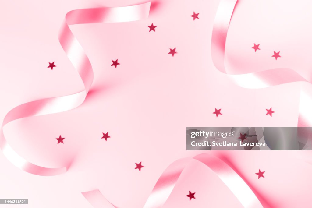 Demonstration of Color of the year 2023. Color of the year. Viva Magenta. Silver curly ribbon and confetti stars on pink background. Design decoration party, birthday, anniversary, Christmas, New Year celebration concept.