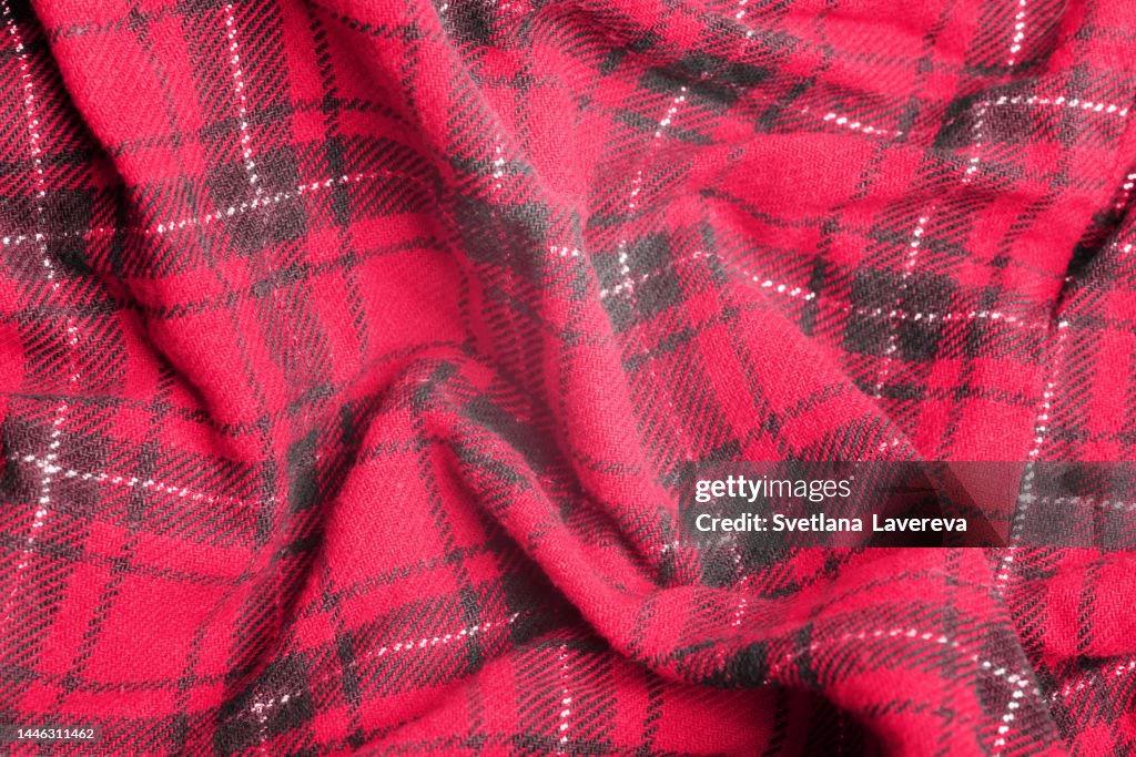 Close up of knitted red, black and green diagonal plaid Scottish seamless pattern. Christmas and New year concept. Demonstration of Color of the year 2023. Color of the year. Viva Magenta.