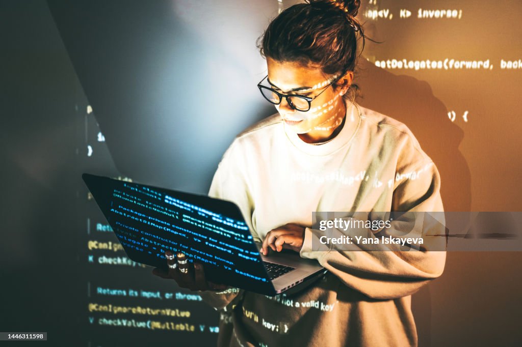 Young woman, CEO and programmer, in smart glasses working with laptop at night