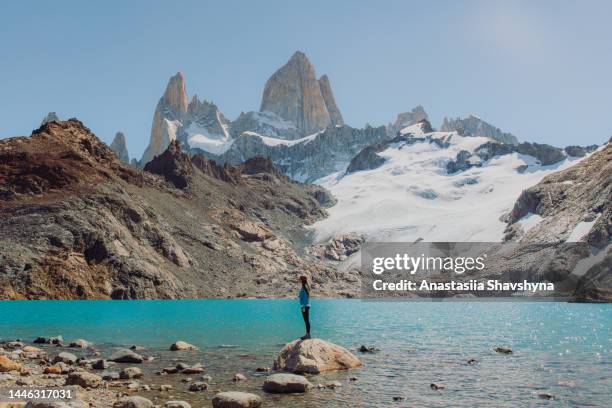 side view of a woman contemplating a view of crystal blue lagoon with fitz roy mountains in patagonia - chalten stock pictures, royalty-free photos & images