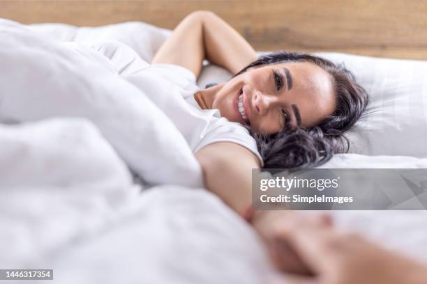 a sleepy smiling woman drags her boyfriend, husband or lover back to bed. - nightwear stock pictures, royalty-free photos & images