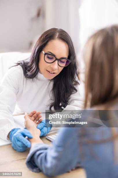 a female dermatologist examines a patient in her office. - dermatologe stock-fotos und bilder