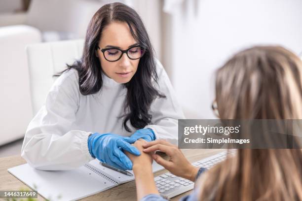 a female dermatologist examines a patient in her office. - melanoma stock pictures, royalty-free photos & images