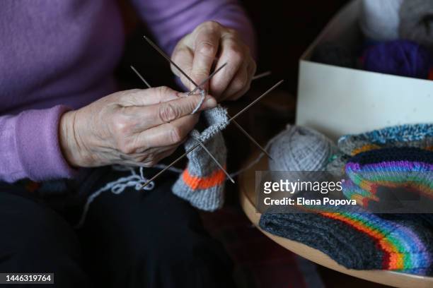 midsection elderly woman knitting colored woolen socks at home - arcas stock pictures, royalty-free photos & images