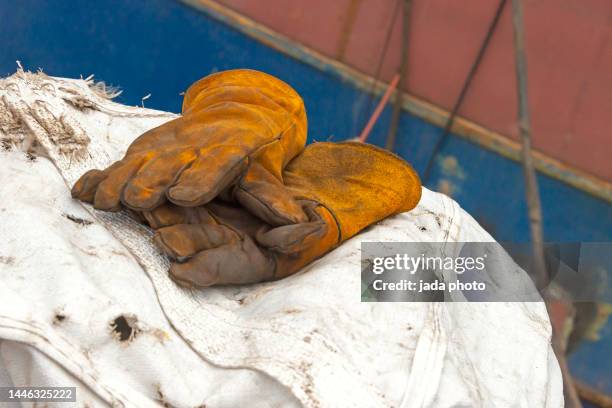 two brown leather work gloves lie on white tarpaulin - brown glove stock pictures, royalty-free photos & images