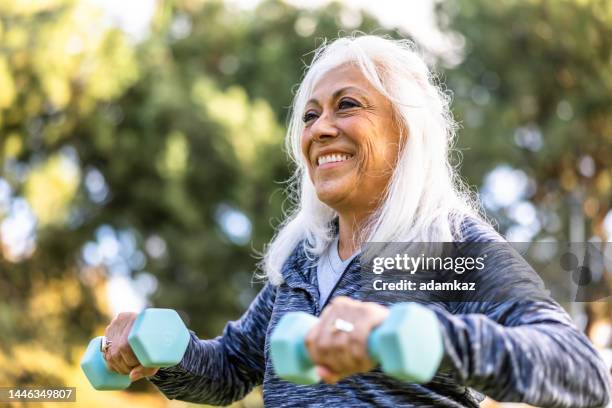 mujer hispana mayor que hace ejercicio con pesas - entrenamiento de fuerza fotografías e imágenes de stock