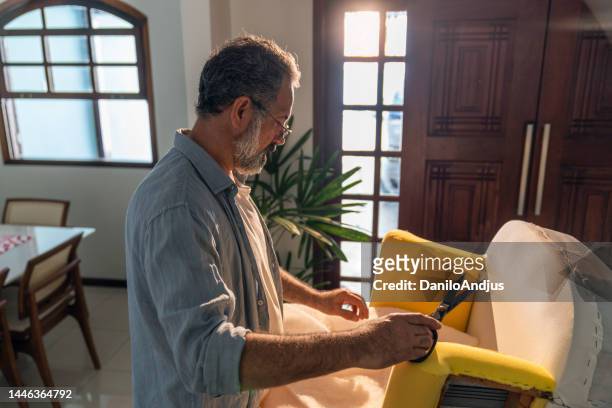 彼の新しいアームチェアに取り組んでいる熟練した家具職人 - 張り椅子 ストックフォトと画像