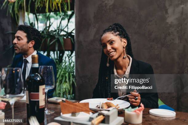 an elegant young adult woman is talking with colleagues at the restaurant - 19 years old dinner stock pictures, royalty-free photos & images