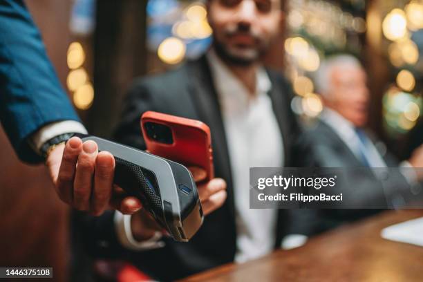 un hombre está pagando la cuenta en el restaurante usando su teléfono inteligente - pago por móvil fotografías e imágenes de stock