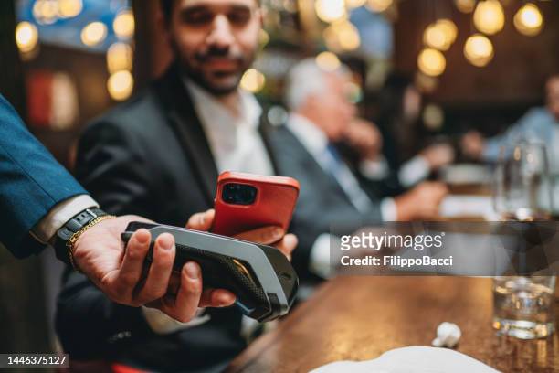 ein mann bezahlt die rechnung im restaurant mit seinem smartphone - apple pay mobile payment stock-fotos und bilder