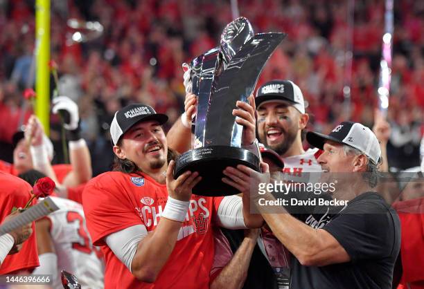 Cameron Rising, Devin Kaufusi and head coach Kyle Whittingham of the Utah Utes celebrate with the Schwabacher Trophy after defeating the USC Trojans...