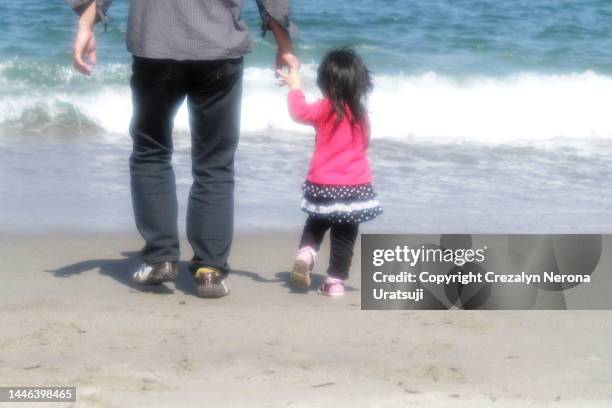 family at the beach. father and child holding hands,walking to the sea - レギンス　 ストックフォトと画像