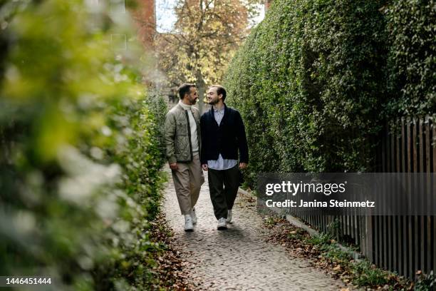 loving gay couple walking between hedges in autumn - atraer fotografías e imágenes de stock