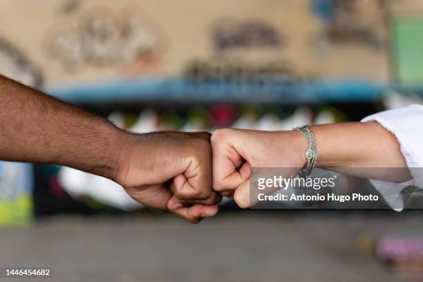 black man and white woman clenching their fists. union concept. stop racism. graffiti wall background. - european union abstract stock-fotos und bilder