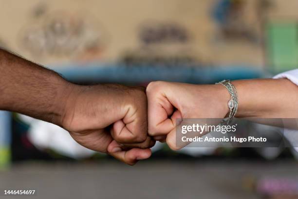 black man and white woman clenching their fists. union concept. stop racism. graffiti wall background. - handshake abstract stock pictures, royalty-free photos & images