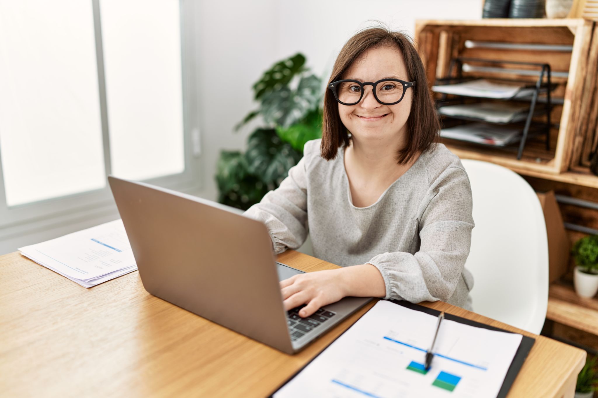Brunette woman with down syndrome working using laptop at business office Brunette woman with down syndrome working using laptop at business office
