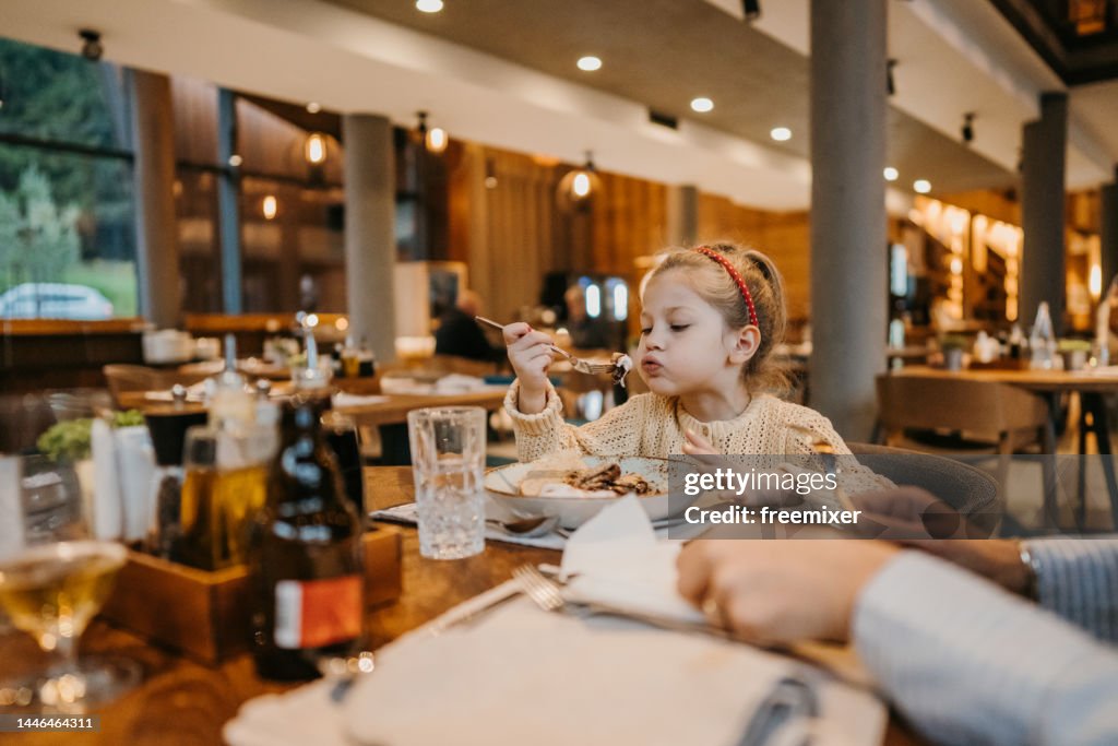 Kleines Mädchen isst Pfannkuchen im Restaurant