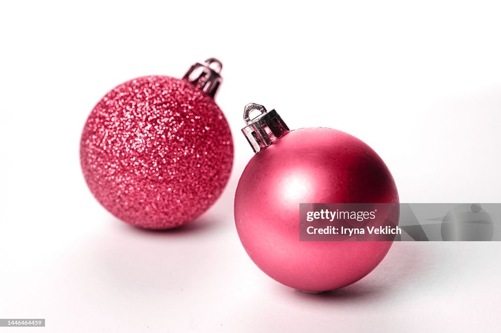 Two Christmas balls in red Viva Magenta Color of The Year 2023 on white color background.