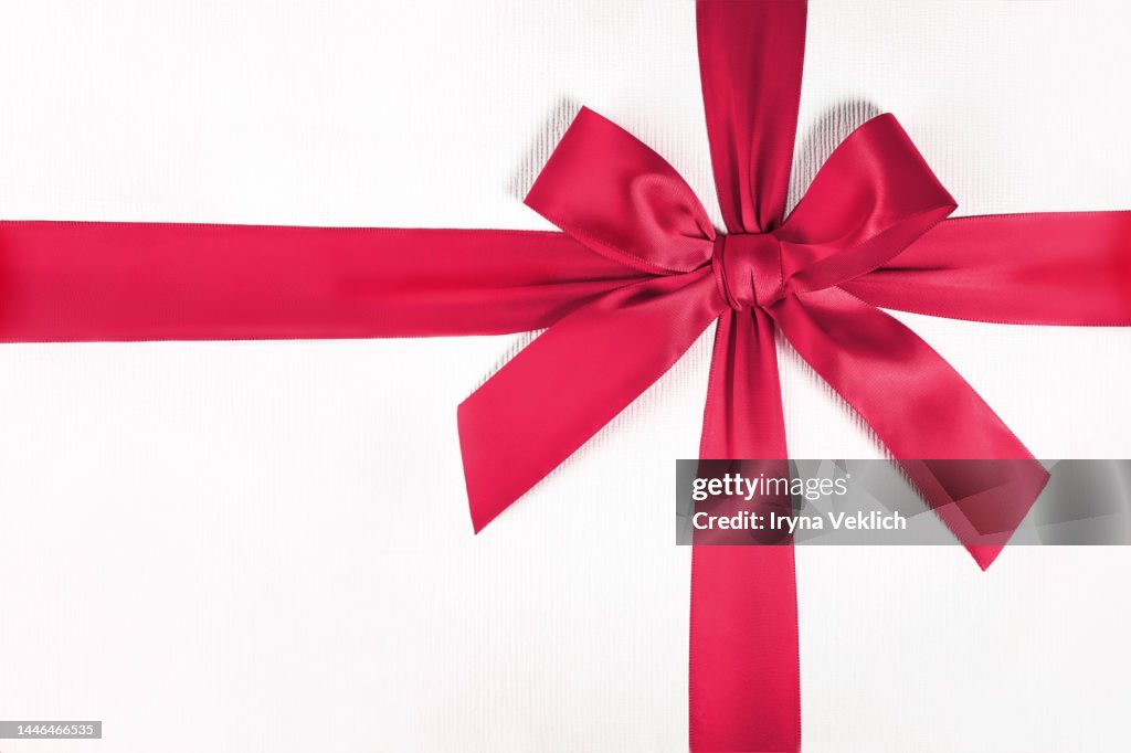 Xmas present, gift, congratulation. Winter Holidays and Black Friday concept with gift box and tied bow in trendy Viva Magenta Color of The Year 2023 color.