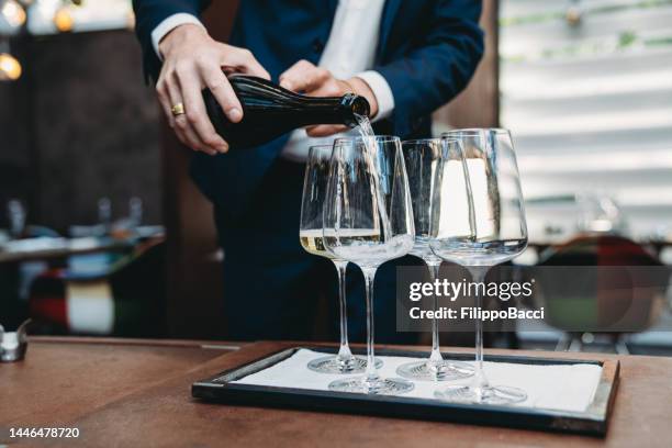 a waiter is pouring prosecco into glasses at the restaurant - glass of prosecco stockfoto's en -beelden