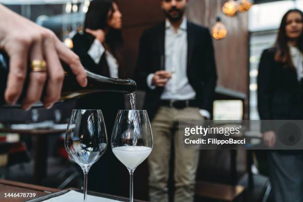 un cameriere sta versando il prosecco nei bicchieri del ristorante - mestiere nella ristorazione foto e immagini stock