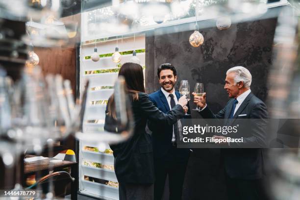 geschäftsleute unterhalten sich und stoßen während eines teambuilding-events in einem luxusrestaurant zusammen - aperitif stock-fotos und bilder