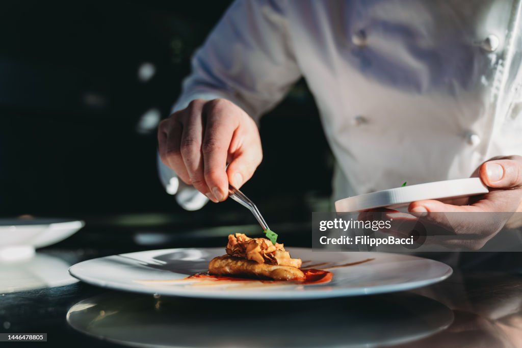 Uno chef sta finendo la preparazione del piatto